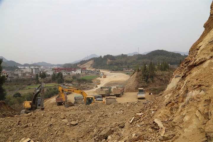 在106国道崇阳县桃树窝至浮溪桥段改扩建工程现场,机器轰鸣,各类运输